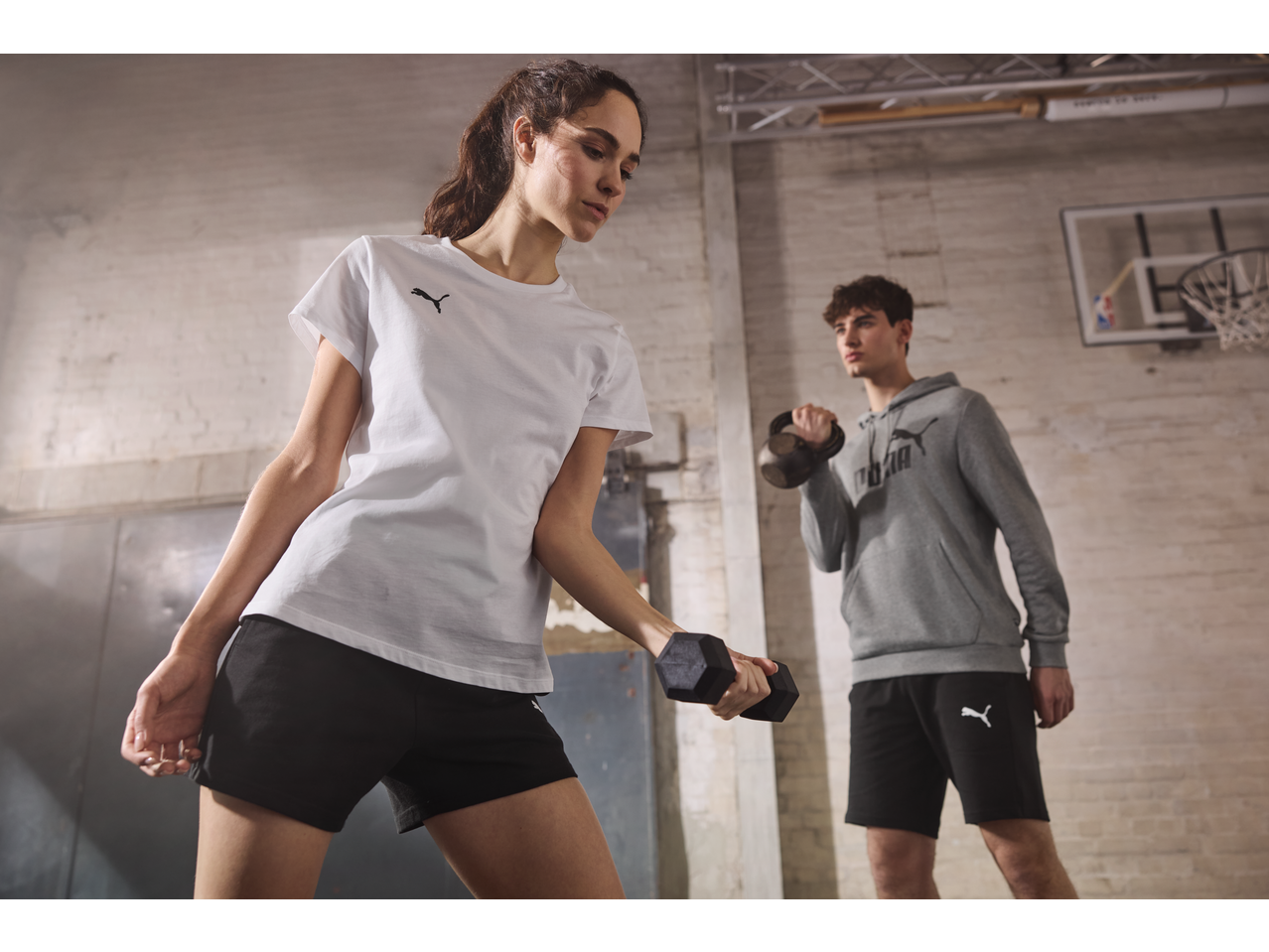 Femeie în tricou și pantaloni scurți PUMA, bărbat în hanorac și pantaloni scurți PUMA antrenându-se.