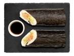 Két sushi tekercs fekete kőlapra téve szójaszósszal.