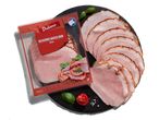 Szeletelt sült sonka Dulano csomagolásban, mellette további szeletek egy tányéron.