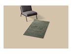 A green bath mat with a rose pattern next to a grey armchair