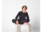 Boy wearing dark blue esmara® Kids' Christmas Velour Pyjamas with festive patterns, sitting on a stool.