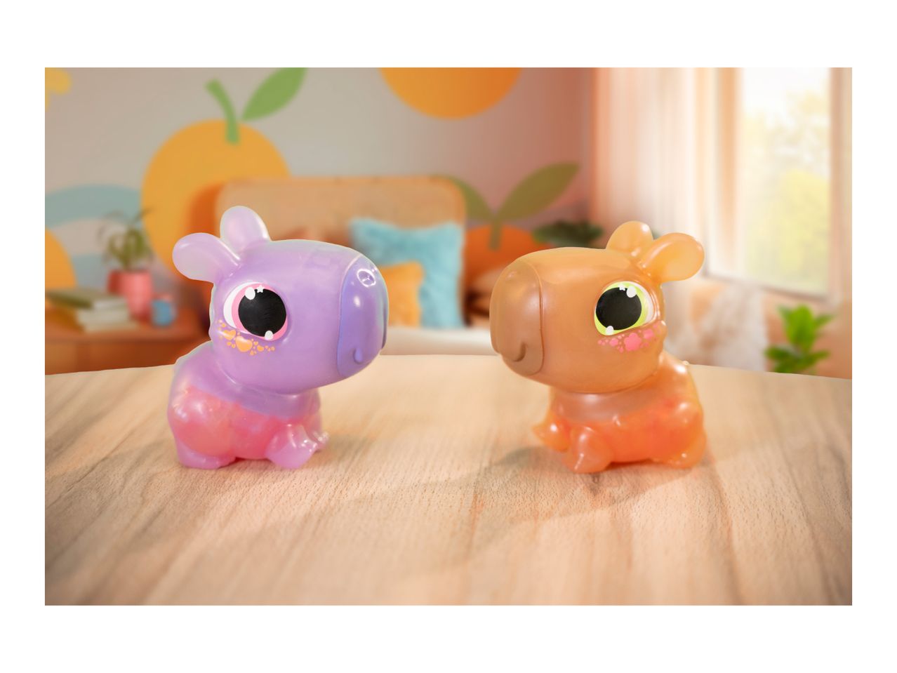 Two colorful, translucent animal toys with large eyes on a wooden surface in a bright room.