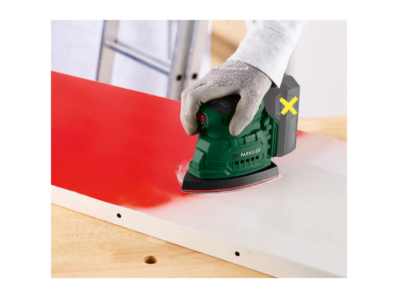 A cordless multi-sander being used to sand a painted wooden board.