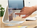 O mână atașează fotografii și notițe pe un ecran iMac.