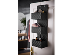 Black hanging organizer with three baskets, holding beauty and personal care products, hanging on a white door.