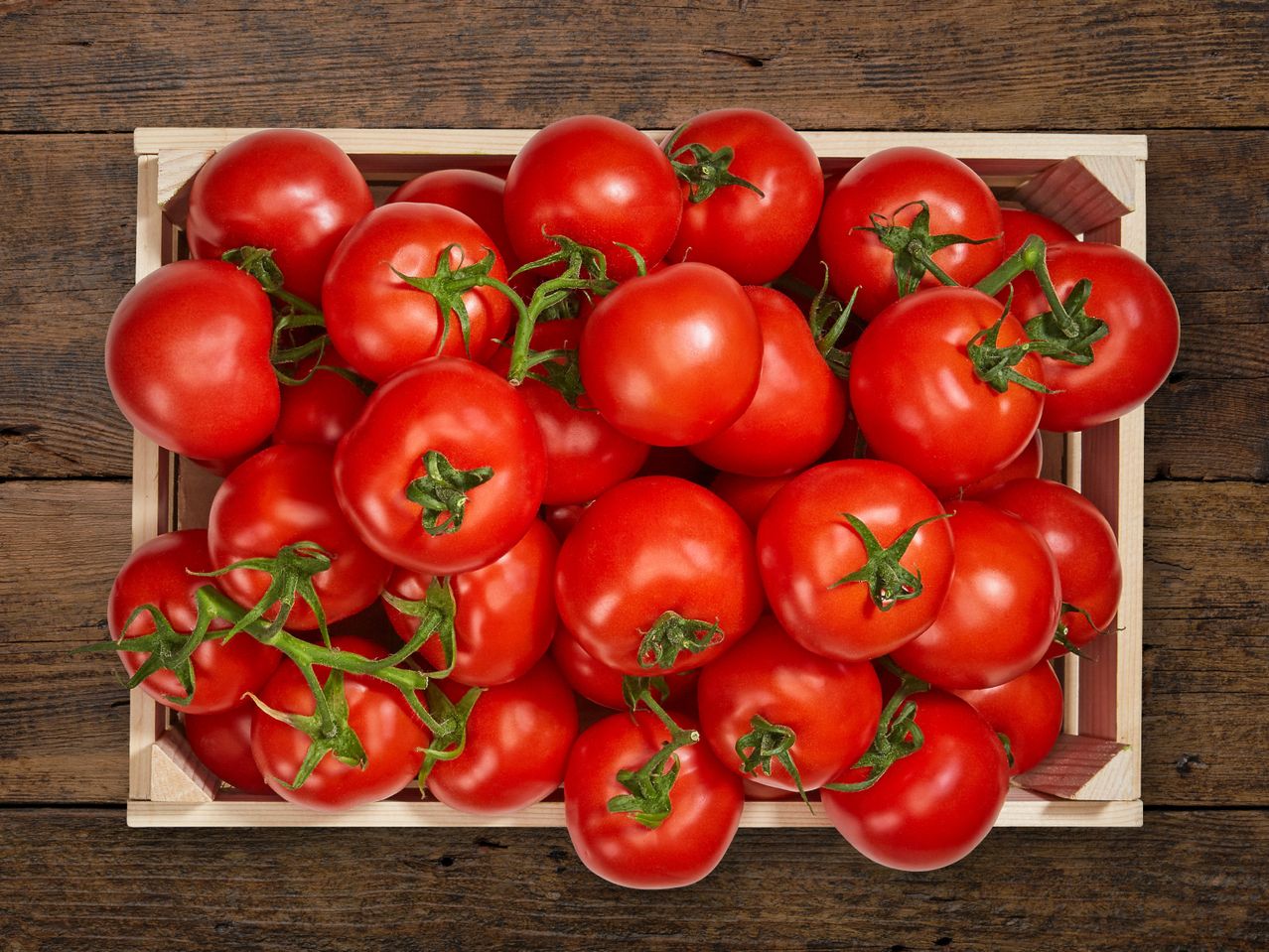 Kiste mit reifen roten Tomaten auf Holz.