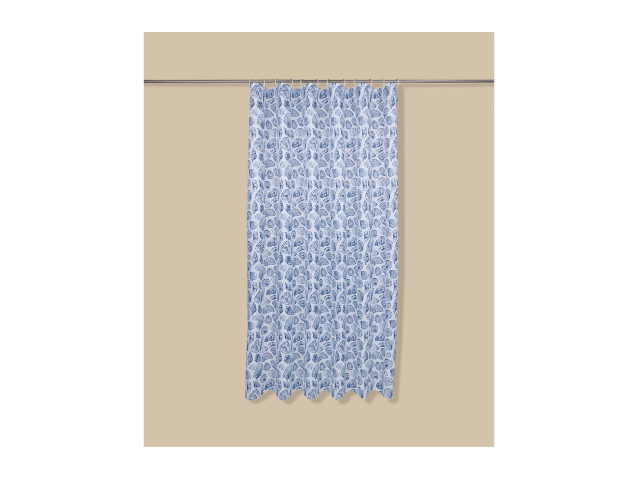 Blue and white seashell pattern shower curtain hanging on a silver rod against a beige wall.