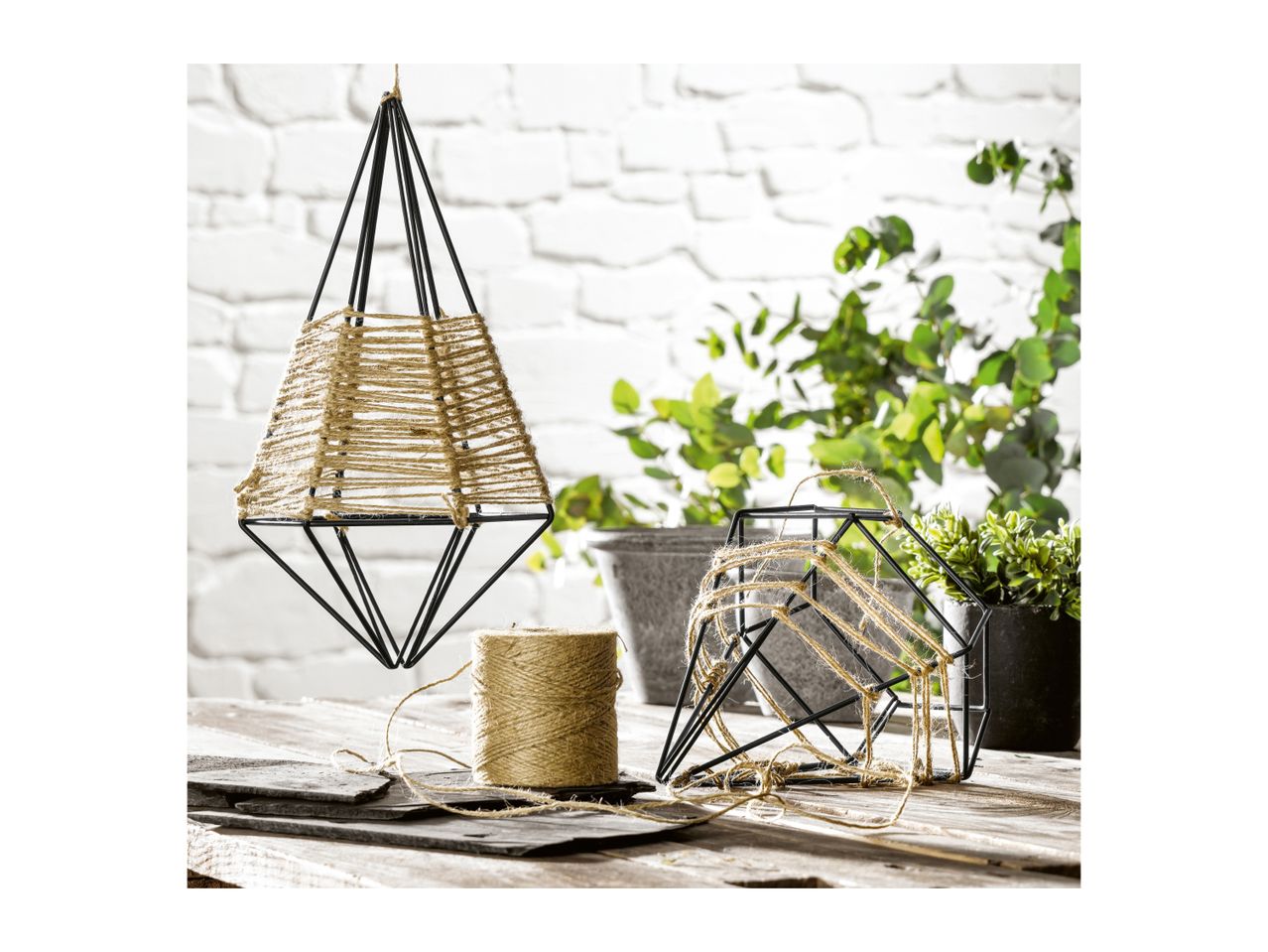 Geometric metal hanging planters wrapped in natural jute twine on a rustic wooden table.