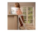 Child on a learning tower in a kitchen, looking at a golden faucet.