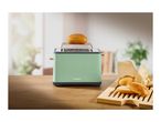 A light green SilverCrest toaster with a bun on top, and more buns on a wooden board.