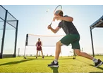 Conjunto de badminton CRIVIT com dois jogadores num campo de relva artificial.