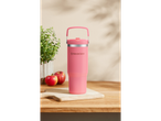 A pink SilverCrest travel mug with a carrying handle sits on a wooden cutting board.