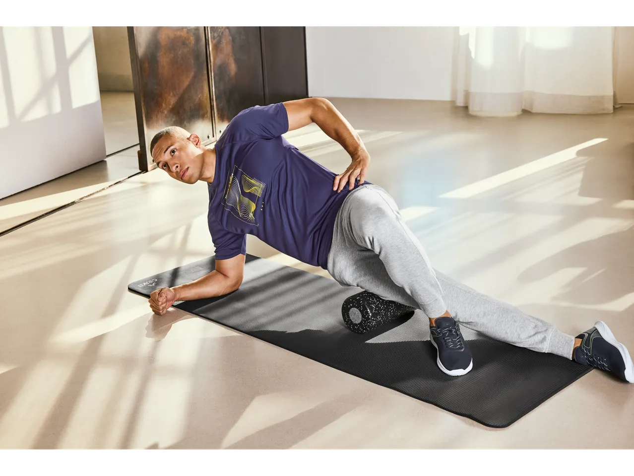 Man using a fitness mat and foam roller.