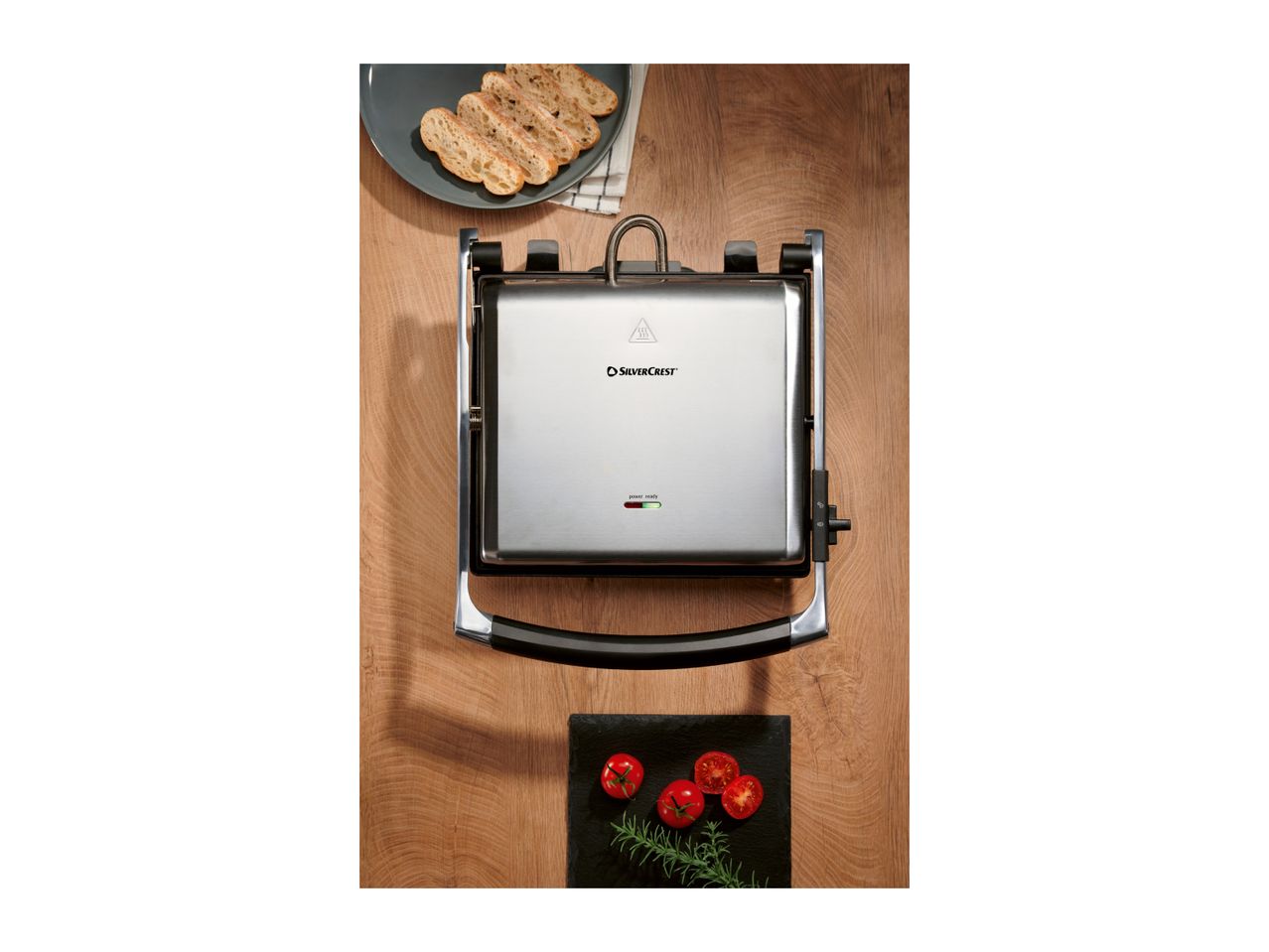 SilverCrest grill with bread slices and tomatoes on a wooden surface.