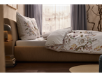 A beige bed with floral bedding sits near a window, showcasing a calm and sophisticated bedroom setting.