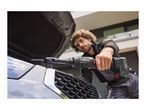 A man uses a cordless ratchet wrench to work on a car engine under the open hood.