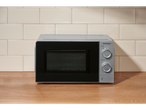 Micro-ondas SILVERCREST® de 700W numa bancada de madeira com parede de azulejos.