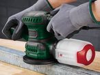 Close-up of a Parkside random orbital sander in use, showcasing its dust collection system.