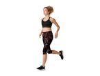 Woman running in a black sports bra with a front zipper and patterned capri leggings.