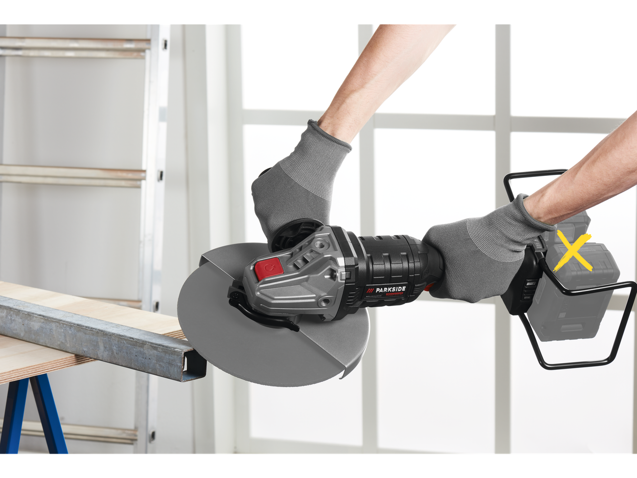 Moški v rokavicah drži kotno brusilko Parkside, pripravljen za rezanje kovine.