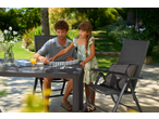 Father and daughter playing dominoes at an outdoor dining table with chairs in a garden.
