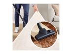 Man lifting a rug to reveal dirt being vacuumed by a vacuum cleaner.