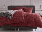 Bett mit roter Paisley-Bettwäsche und grauem Überwurf