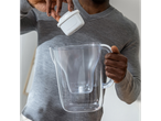 A person inserts a Brita water filter into a Brita water pitcher.