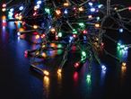 Close-up of tangled colorful LED string lights on a dark, reflective surface.