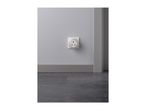 A white night light plugged into a wall socket above a dark grey baseboard and floor.