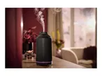 Black ribbed aroma diffuser emitting mist on a wooden table in a cozy room