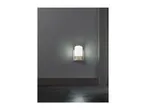 A white night light with a motion sensor illuminates a dark hallway.