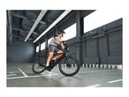 Man in cycling gear riding an electric bike in a modern indoor space.