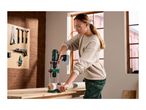 A woman using a drill guide attachment to drill a hole into a wooden post on a workbench.