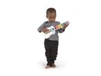 A young boy playing a white and wooden toy guitar with colorful animal buttons.