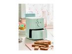 A mint green air fryer on a kitchen counter with cupcakes and sliced bread.