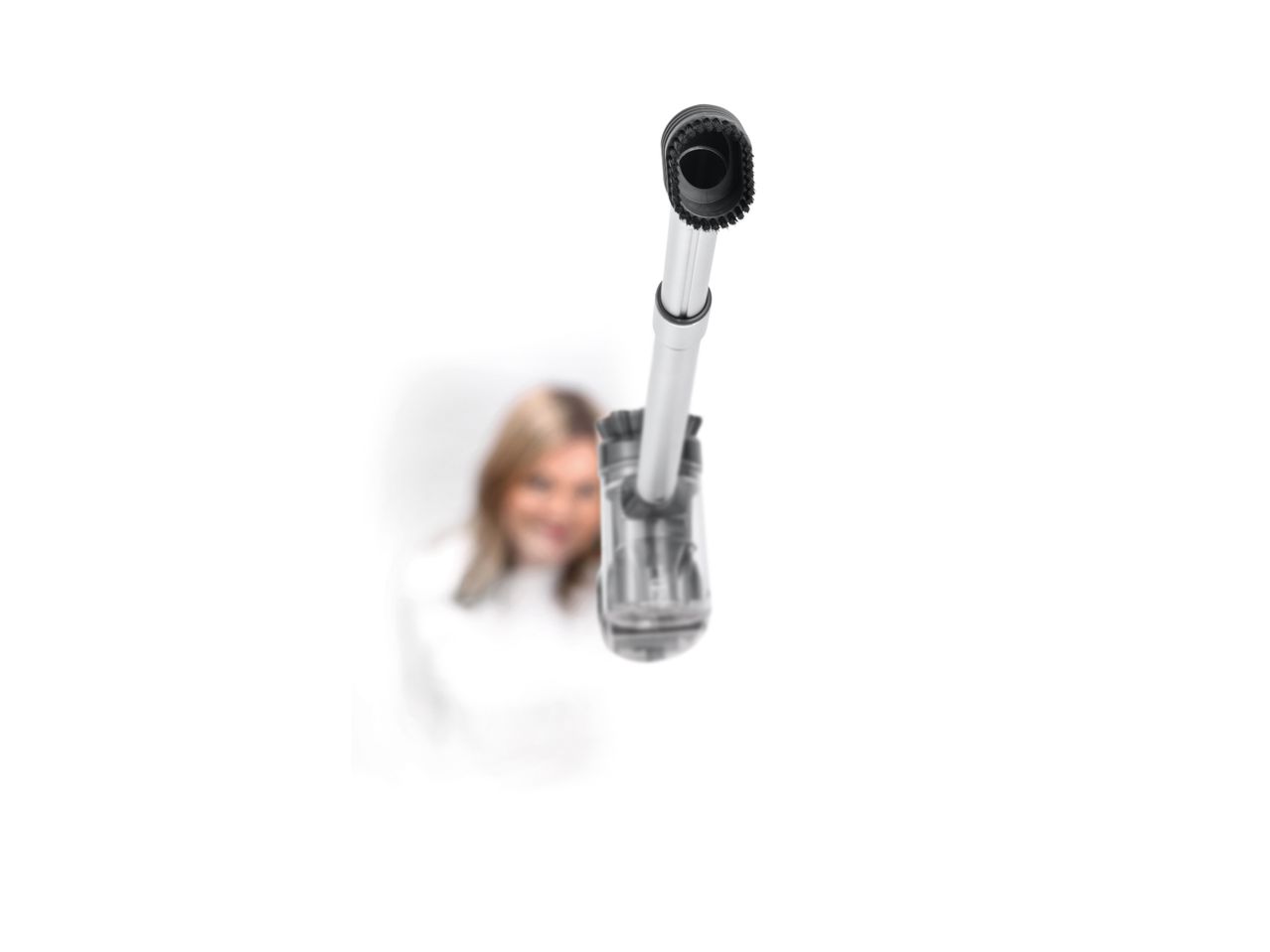 A woman holding a handheld vacuum cleaner, pointing it towards the viewer.