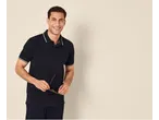 Homem sorridente de polo e calças azul-marinho, segurando óculos.