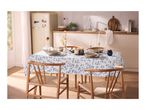 Dining table with a blue leaf-patterned tablecloth, set with plates, glasses, and cutlery.