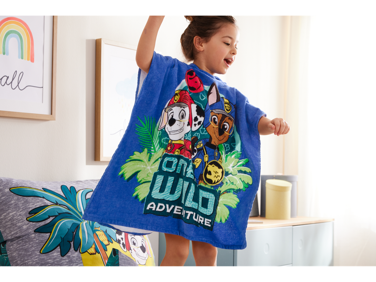 Criança feliz usando roupão de banho Paw Patrol, pulando na cama.