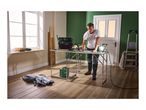 Man working at a folding workbench with a tool bag, drill, and work light.