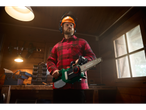 Man in a Parkside overshirt and safety gear holding a Parkside chainsaw in a workshop.
