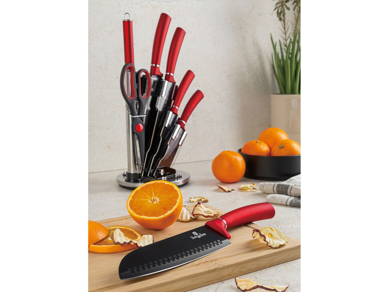 Berlinger Haus knife set with red handles, oranges, and dried fruit on a kitchen counter.