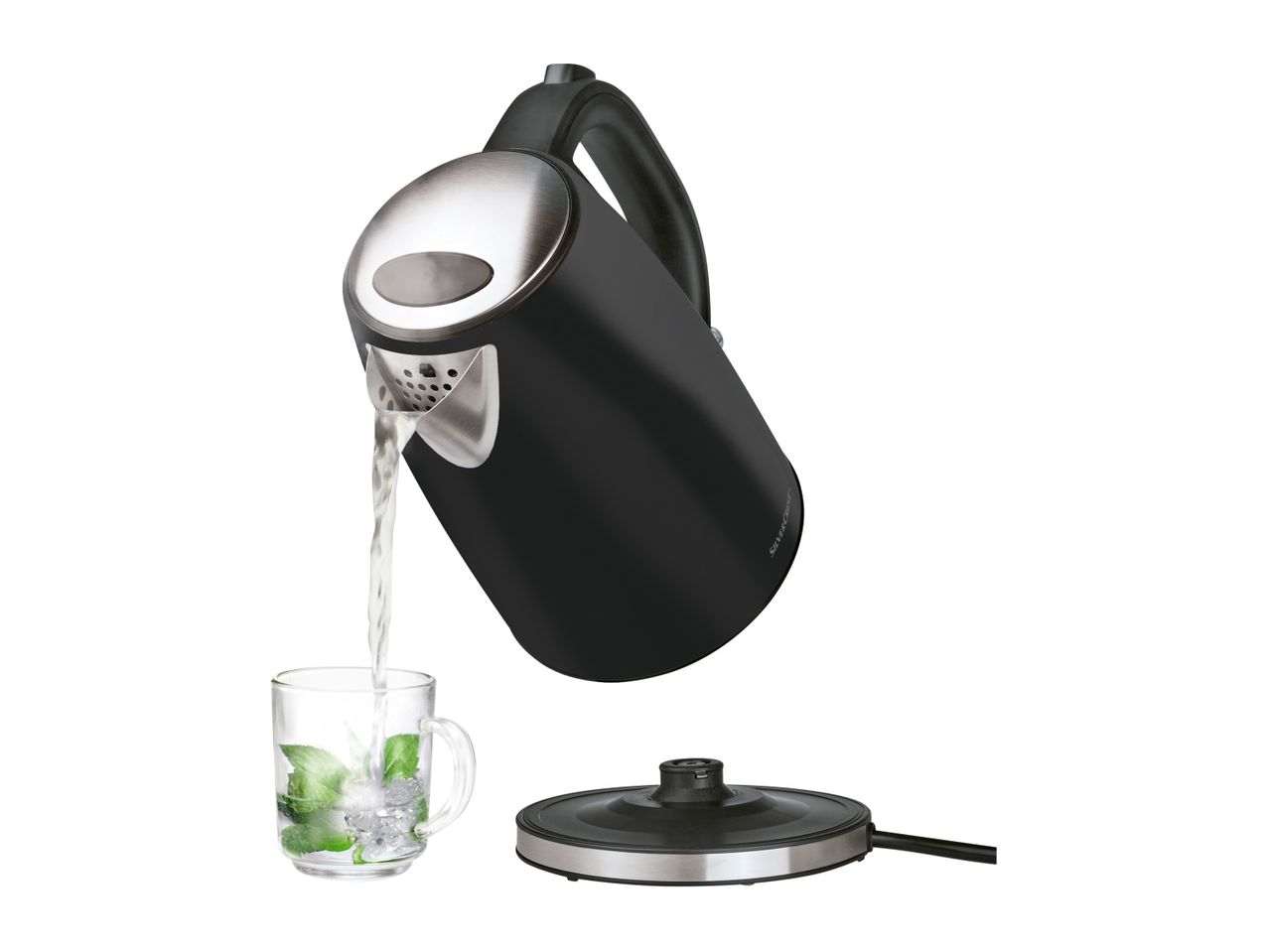 A black electric kettle pours water into a glass, sitting on its base.