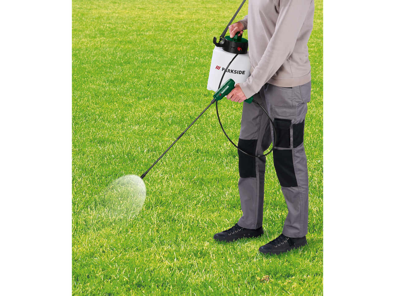 Person spraying grass with a Parkside cordless sprayer.