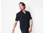 Model masculin îmbrăcat într-o cămașă și pantaloni scurți negri.