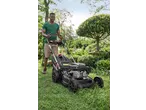 Man mowing a lawn with a black and red lawnmower in a garden.
