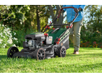 Parkside® Petrol Lawnmower being pushed across a green lawn by a person.