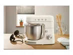 Cream-colored stand mixer with '1973' on it, stainless steel bowl, on a wooden counter.