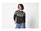Woman in a dark gray fair isle sweater and blue jeans.